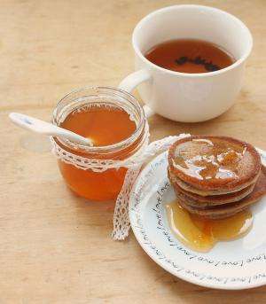 баночка абрикосового сиропа, оладьи и чашка чая
