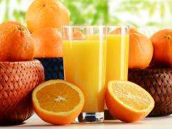 два стакана апельсинового сока на столе на фоне корзинок с апельсинами