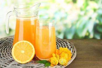 прозрачный графин и стакан апельсинового сока, половина апельсина на столе