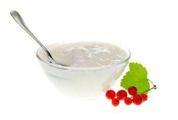 йогурт в стеклянной мисочке и ягоды красной смородины