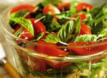 прозрачная салатница с помидорами и зелеными листьями базилика