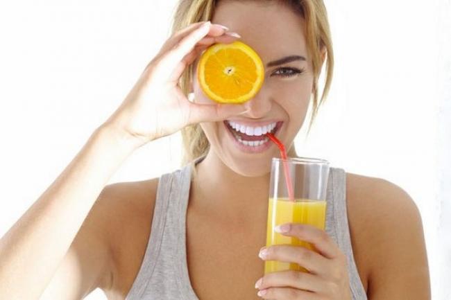 девушка со стаканом апельсинового сока и половинкой апельсина в руке
