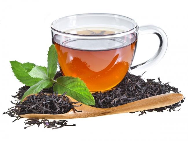 чашка горячего черного чая и листья сушеные и свежие