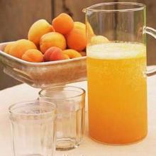 абрикосовый сок в графине на столе, стаканы и свежие абрикосы в тарелке для фруктов