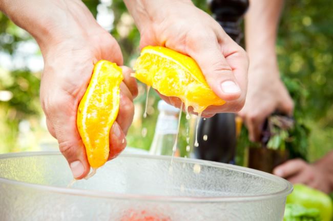 выдавливание апельсинового сока из половинок апельсина при помощи рук